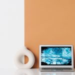 Minimalist workspace featuring a laptop with digital marketing text, a ceramic vase, and dried grass. — 5 Ways a Strong Backl