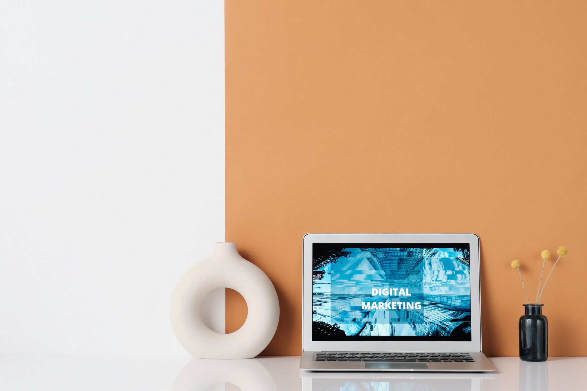 Minimalist workspace featuring a laptop with digital marketing text, a ceramic vase, and dried grass. — 5 Ways a Strong Backl