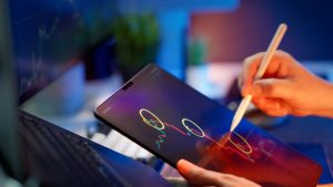 Person analyzing cryptocurrency trends on a tablet with digital pen. — A Funded Trading Account Lets You Trade Without Capita