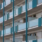 Exterior view of a modern apartment building with multiple blue balconies, showcasing contemporary architectural design. — Ap
