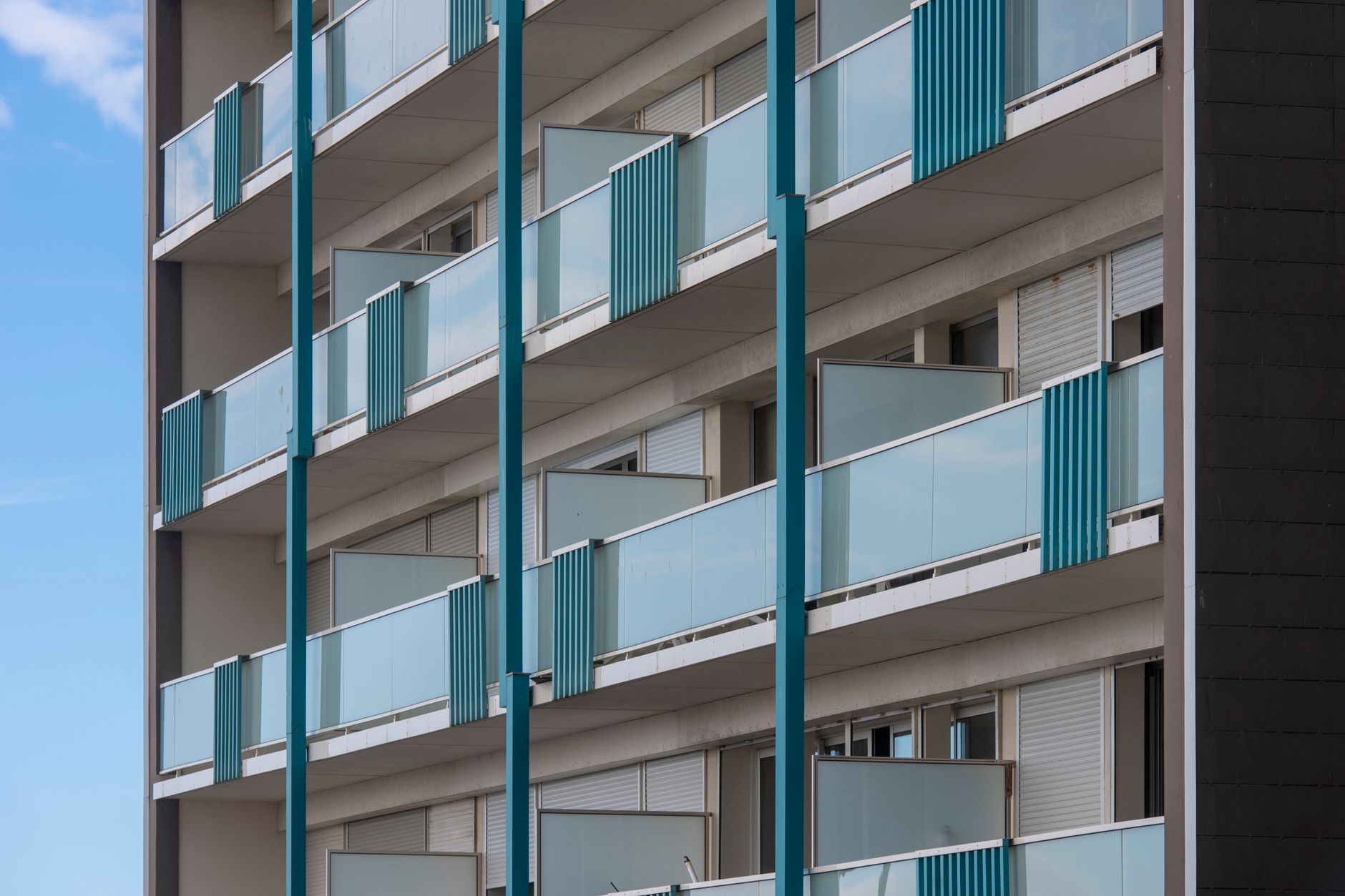Exterior view of a modern apartment building with multiple blue balconies, showcasing contemporary architectural design. — Ap