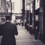 Man in a suit walking down a city street in a lonely, urban setting. — Choose a forex broker that offers fast execution and t