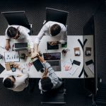 High angle view of colleagues collaborating around a conference table in a modern office setting. — Community Upliftment Thro