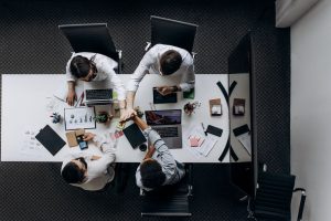 High angle view of colleagues collaborating around a conference table in a modern office setting. — Community Upliftment Thro