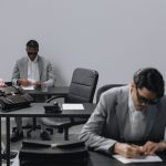 Business office with diverse employees in gray suits working at desks in an indoor setting. — Dr. James Morales: A Trusted Au