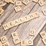Wooden letter tiles arranged on a wooden surface spelling out 'healthy', symbolizing wellness. — Dr. Zachary Lipman Bridging