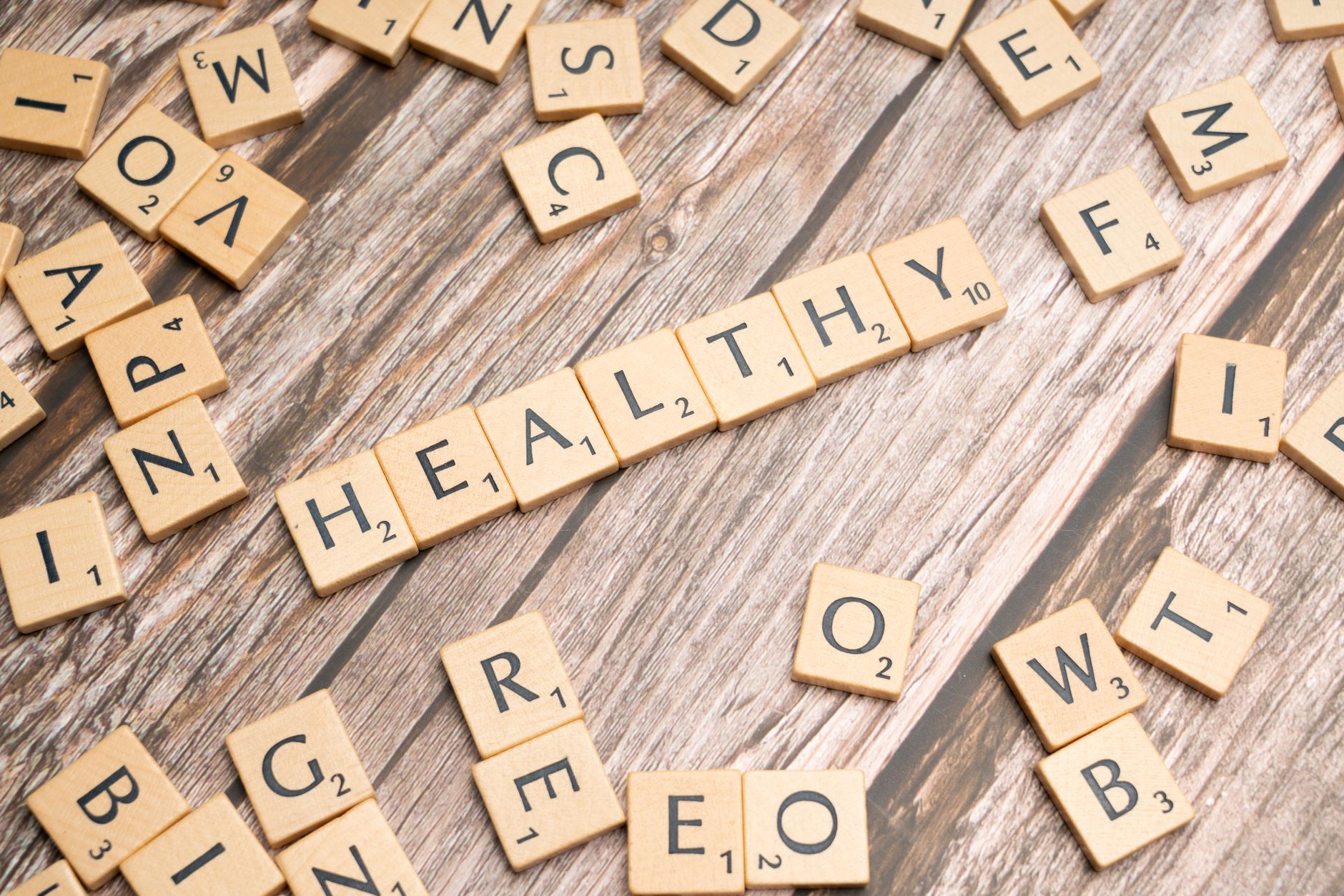 Wooden letter tiles arranged on a wooden surface spelling out 'healthy', symbolizing wellness. — Dr. Zachary Lipman Bridging