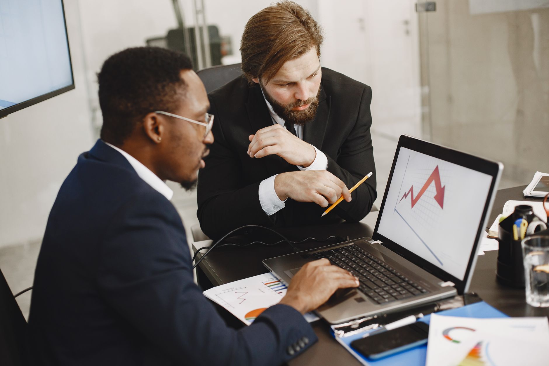 Two business professionals discuss marketing data on a laptop in a modern office. — Elements Brasserie: Enjoy a Perfectly Gri