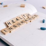 Scrabble tiles spelling 'Health Insurance' on a calendar with pills. — Expert Heart Health Advice from Dr Ian Weisberg on Pal