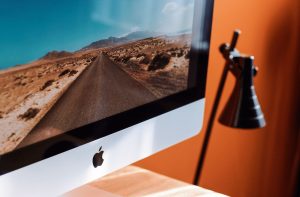 A sleek modern workspace featuring an iMac displaying a desert road and a stylish desk lamp. — How a Simple YouTube Video Emb