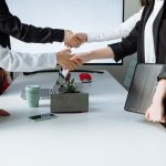 Professionals sealing a deal with a handshake across a conference table during a business meeting. — How Andrew Hillman Drive