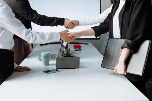 Professionals sealing a deal with a handshake across a conference table during a business meeting. — How Andrew Hillman Drive