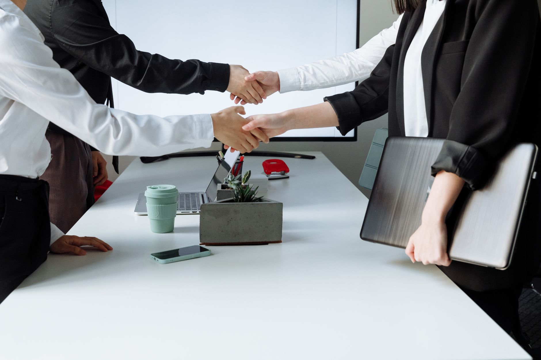 Professionals sealing a deal with a handshake across a conference table during a business meeting. — How Andrew Hillman Drive
