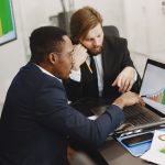 Two business professionals working on growth charts using laptop in an office setting. — How BTCC Academy Is Helping Students