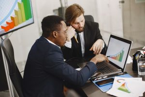 Two business professionals working on growth charts using laptop in an office setting. — How BTCC Academy Is Helping Students