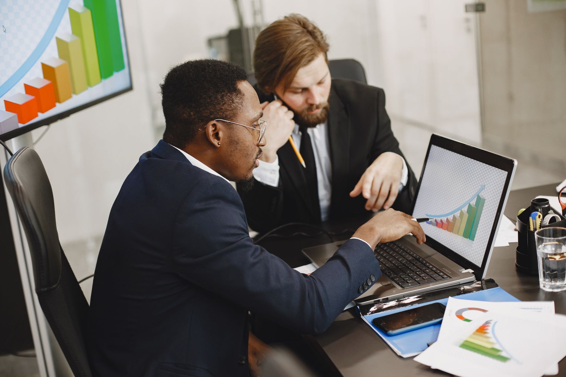 Two business professionals working on growth charts using laptop in an office setting. — How BTCC Academy Is Helping Students