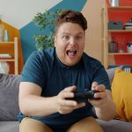 Enthusiastic adult male playing video game on console in colorful, modern living room. — How do Bitcoin trends shape roulette