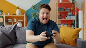 Enthusiastic adult male playing video game on console in colorful, modern living room. — How do Bitcoin trends shape roulette