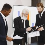 Three businessmen in suits reviewing reports and graphs during an office meeting. — Madrid Zoo Aquarium Adventures for Every