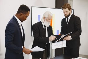 Three businessmen in suits reviewing reports and graphs during an office meeting. — Madrid Zoo Aquarium Adventures for Every