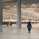 A modern train station interior with passengers walking towards a waiting train. — Move Larger Loads with a Spacious Luton Va
