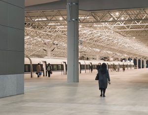 A modern train station interior with passengers walking towards a waiting train. — Move Larger Loads with a Spacious Luton Va