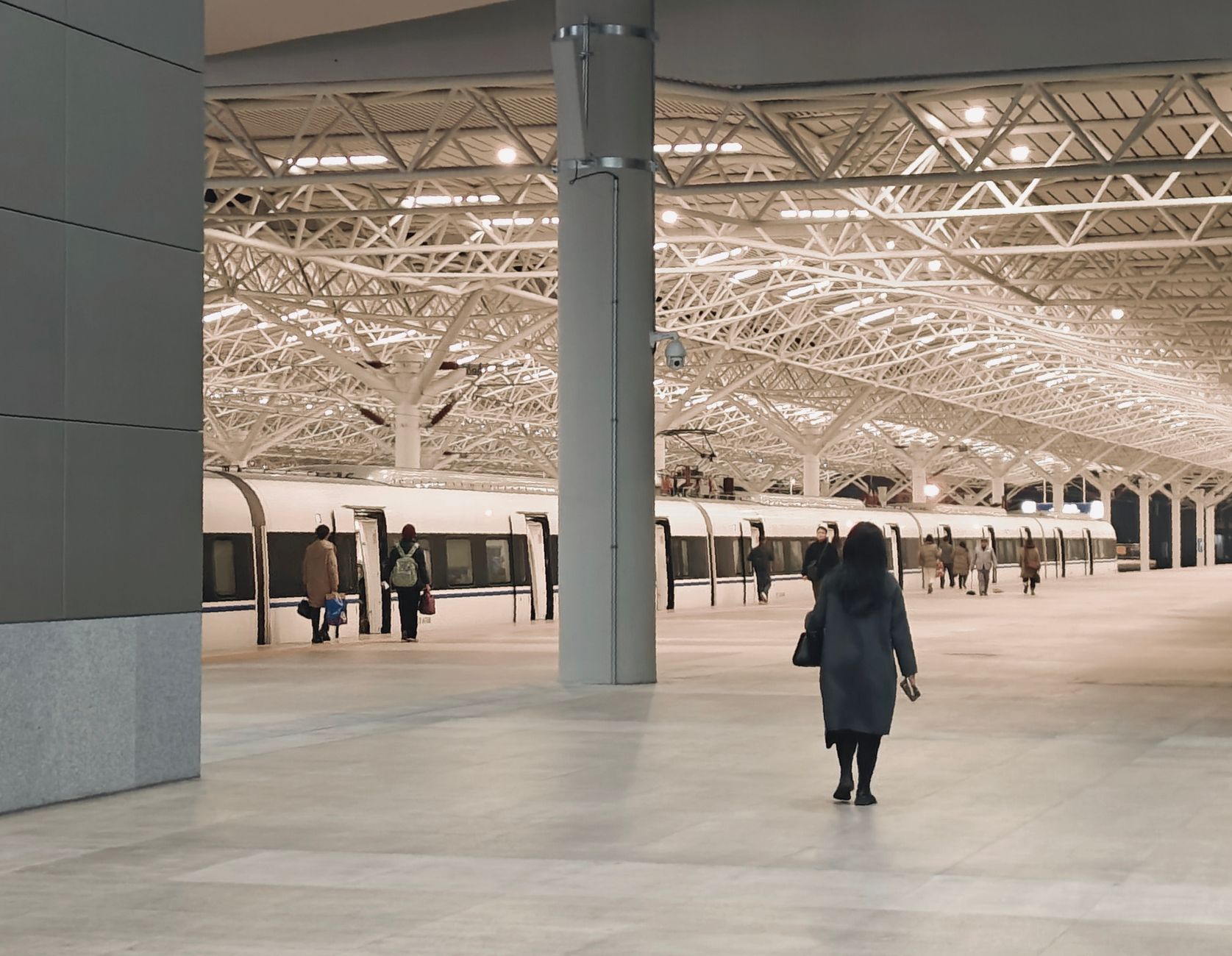 A modern train station interior with passengers walking towards a waiting train. — Move Larger Loads with a Spacious Luton Va