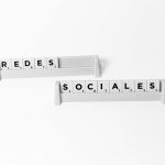 Scrabble tiles arranged to spell 'Redes Sociales', depicting social media on a white background. — Perfil ativo pagando apena