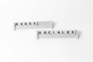 Scrabble tiles arranged to spell 'Redes Sociales', depicting social media on a white background. — Perfil ativo pagando apena