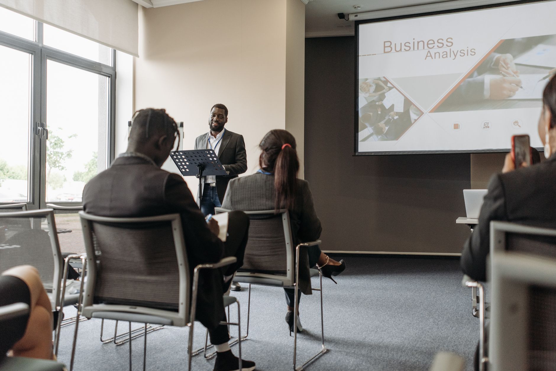A business professional delivering a presentation in a conference room with diverse attendees. — Success Stories: From Part-T