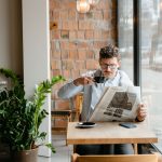 Man sitting indoors with coffee and newspaper, surrounded by plants by the window. — The Impact of Video Marketing on Healthc