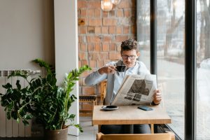 Man sitting indoors with coffee and newspaper, surrounded by plants by the window. — The Impact of Video Marketing on Healthc