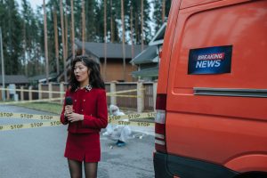Female reporter in red outfit at an outdoor crime scene with warning tape and a news van. — The Path to Instagram Stardom: Bu