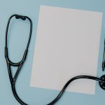 Flat lay of a stethoscope, blank paper, and pen on a blue background. — Tips for Buying Testosterone from Reputable Online Ph