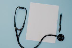 Flat lay of a stethoscope, blank paper, and pen on a blue background. — Tips for Buying Testosterone from Reputable Online Ph