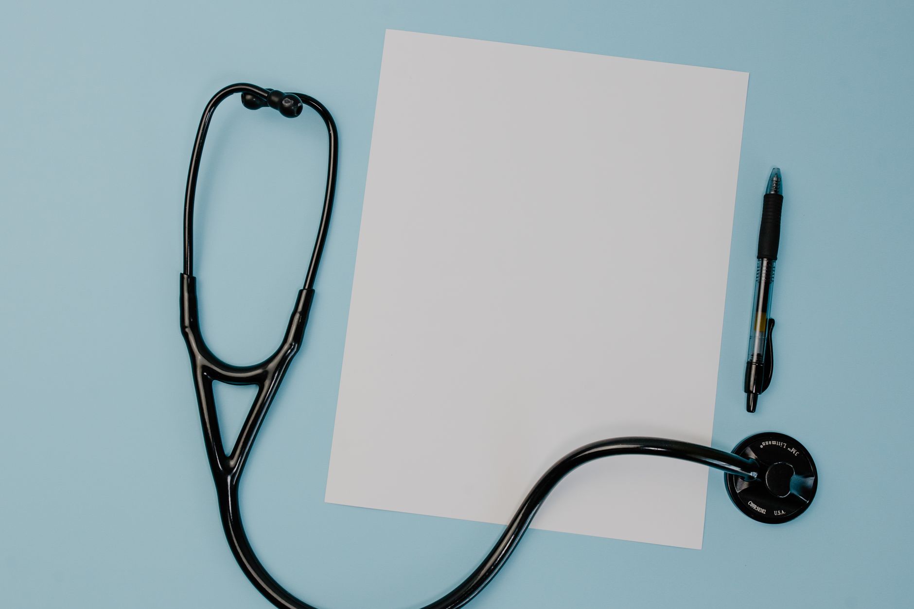 Flat lay of a stethoscope, blank paper, and pen on a blue background. — Tips for Buying Testosterone from Reputable Online Ph