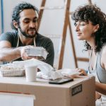 A couple relaxes with takeout food amidst moving boxes in their new home. — Understanding the Psychology Behind Football Bett