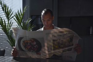 Businessman focused on reading newspaper in a sunny indoor office setting. — What Should I Know About Getting a Roof Inspecti