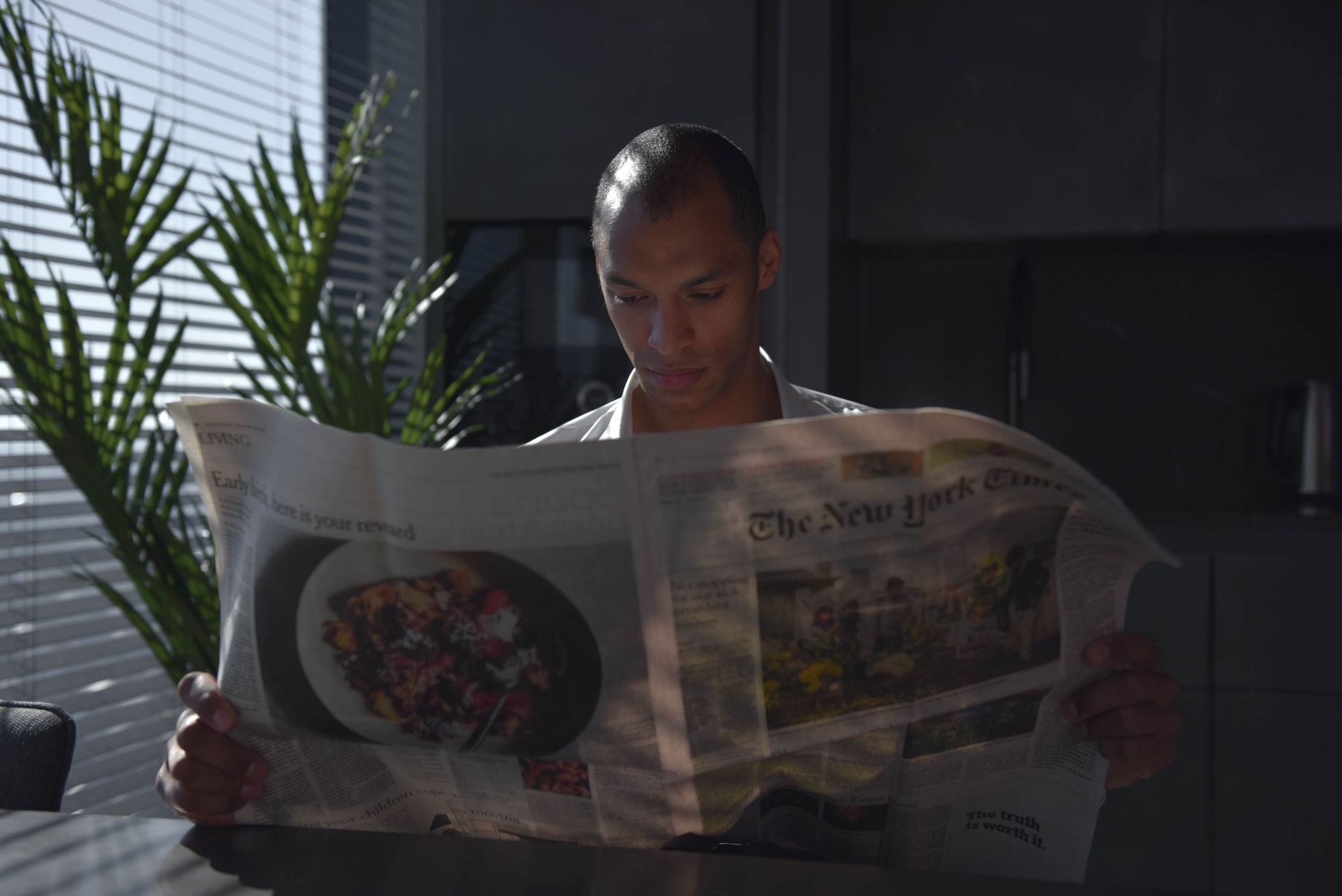 Businessman focused on reading newspaper in a sunny indoor office setting. — What Should I Know About Getting a Roof Inspecti